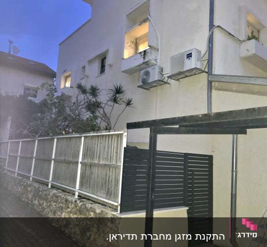 יחידת מיזוג אוויר מותקנת על קיר חיצוני של בניין.
